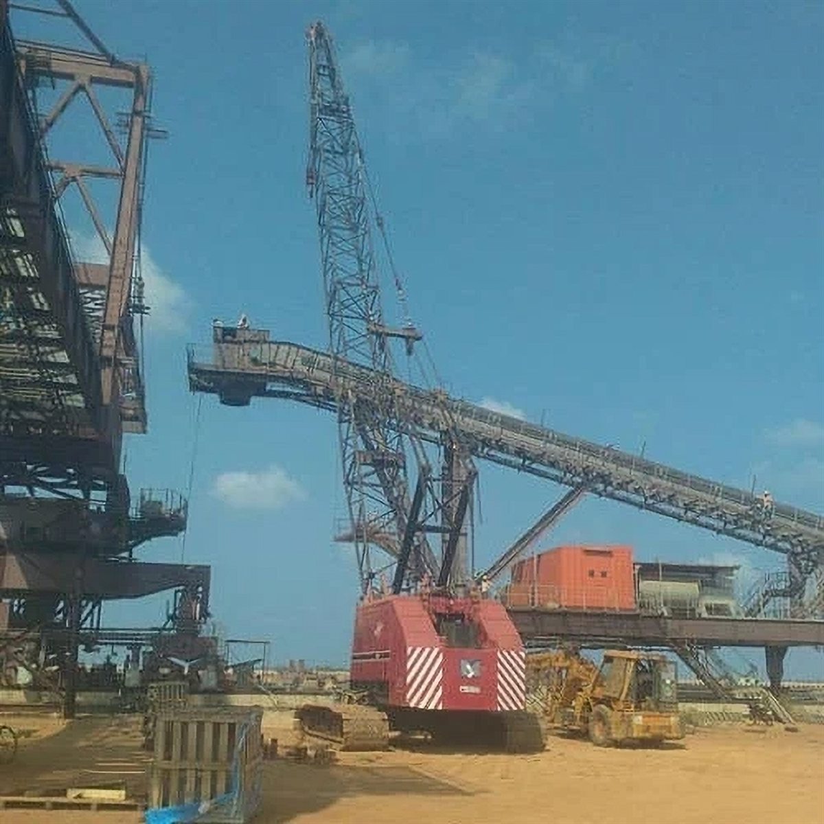 Crawler crane alongside conveyor structures at a port facility